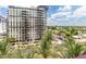 An elevated view of the exterior of a high-rise condominium and city buildings beyond lush palm trees at 4808 N 24Th St # 702, Phoenix, AZ 85016