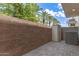 The backyard is composed of stone pavers, a brick fence, and several trees in the background at 5460 S Dillon Cir, Mesa, AZ 85212