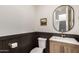 An elegant half-bathroom featuring wainscotting, and a striking round mirror above its single vanity at 5460 S Dillon Cir, Mesa, AZ 85212
