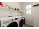 A bright laundry room with modern appliances and a floating shelf above at 5460 S Dillon Cir, Mesa, AZ 85212