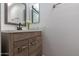 Bathroom with wood-grain vanity, modern hardware, flowers, and a framed mirror at 6044 W Augusta Ave, Glendale, AZ 85301