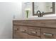 Close-up of bathroom vanity with wood-grain cabinets, white countertops, and modern fixtures at 6044 W Augusta Ave, Glendale, AZ 85301