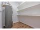 Utility room with water heater, laminate floors, and white cinder block walls with shelving at 6044 W Augusta Ave, Glendale, AZ 85301