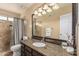 Bathroom featuring a granite countertop, a large mirror with decorative lighting, and a tiled shower at 6133 E Saddleback St, Mesa, AZ 85215
