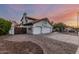 Charming two-story home with a three-car garage, complemented by well-maintained landscaping and sunset skies at 6133 E Saddleback St, Mesa, AZ 85215