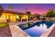 Inviting backyard pool area with covered patio and lush greenery illuminated by stylish string lights at dusk at 650 E Silver Creek Rd, Gilbert, AZ 85296