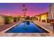 Backyard pool with patio, umbrella, and palm trees against a vibrant sunset sky at 650 E Silver Creek Rd, Gilbert, AZ 85296