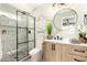Bright bathroom featuring a round mirror, wooden vanity, and glass shower at 6751 W Cameron Dr, Peoria, AZ 85345