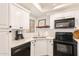 This galley kitchen features white cabinetry, subway tile backsplash, stainless sink, and modern black appliances at 7008 E Gold Dust Ave # 236, Scottsdale, AZ 85253