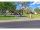 Community playground with colorful equipment and a paved walkway among mature trees on a sunny day at 715 N Cholla St, Chandler, AZ 85224