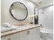 Bright bathroom featuring a round mirror, white cabinets, and herringbone tile in the shower at 7955 E Chaparral Rd # 115, Scottsdale, AZ 85250