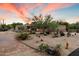 Southwest-style house with desert landscaping, a brick driveway, and a colorful sunset in the background at 8035 E Paraiso Dr, Scottsdale, AZ 85255