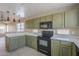 Open kitchen with modern appliances, tile floors, green cabinets, and pass-through to the living room at 823 W Bradford Dr, Gilbert, AZ 85233
