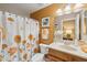 Well-lit bathroom featuring an oak vanity, a shower-tub combo, and a floral shower curtain at 11320 E Newcastle Ave, Mesa, AZ 85209