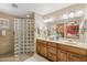 Bathroom featuring a double vanity, framed mirrors, neutral paint, and a tiled walk-in shower at 11320 E Newcastle Ave, Mesa, AZ 85209