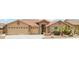 Inviting home exterior showcasing a three-car garage, desert landscaping, and stone accents at 11320 E Newcastle Ave, Mesa, AZ 85209