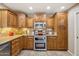A close up on the kitchen with wooden cabinetry, granite counters, tile backsplash, and stainless steel appliances at 11320 E Newcastle Ave, Mesa, AZ 85209