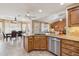 Kitchen with stainless steel dishwasher, wooden cabinets, granite countertops, and an adjacent dining area at 11320 E Newcastle Ave, Mesa, AZ 85209