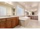 Spa-like bathroom featuring a jetted tub, wooden cabinets, and dual sinks at 14494 W Yucatan St, Surprise, AZ 85379
