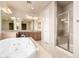Well-lit bathroom featuring a jacuzzi tub, walk-in shower and dual sinks with a large mirror at 14494 W Yucatan St, Surprise, AZ 85379