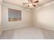 Bright bedroom offers neutral carpet, ceiling fan, and a large window with blinds at 14494 W Yucatan St, Surprise, AZ 85379
