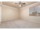 Bright bedroom offers neutral carpet, ceiling fan, and a large window with blinds at 14494 W Yucatan St, Surprise, AZ 85379