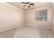 Bright bedroom offers neutral carpet, ceiling fan, and a large window with blinds at 14494 W Yucatan St, Surprise, AZ 85379