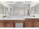 Bathroom featuring double sinks, framed mirrors, and a glass block window at 14676 W Banff Ln, Surprise, AZ 85379