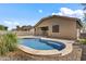 Backyard with a freeform swimming pool, rock landscaping, and covered patio at 14676 W Banff Ln, Surprise, AZ 85379