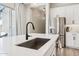 Close-up of the kitchen island featuring a stainless steel sink, black faucet, and white countertop at 1865 N 141St Ave, Goodyear, AZ 85395