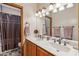 Bathroom with double sinks, wooden cabinets, framed mirror, and shower with decorative curtain at 18851 N 69Th Ave, Glendale, AZ 85308