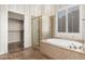 Bright bathroom featuring a shower, soaker tub, and a walk in closet with shelving and towel rack at 22222 N Pedregosa Dr, Sun City West, AZ 85375
