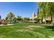 Expansive green lawn with a fountain, set against a charming building and blue sky at 22222 N Pedregosa Dr, Sun City West, AZ 85375