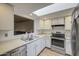 Well-lit kitchen with stainless steel appliances, white cabinetry, and an open view into the living area at 2505 E Desert Cactus St, Phoenix, AZ 85032