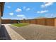 Fully fenced backyard including gravel landscaping, turf area, and a playground at 25974 W Horsham Dr, Buckeye, AZ 85396