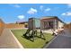 Landscaped backyard featuring artificial turf, a playset, and a covered patio, perfect for outdoor enjoyment at 25974 W Horsham Dr, Buckeye, AZ 85396