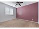 This bedroom has a ceiling fan and a window with shutters, with an accent wall and neutral carpet at 25974 W Horsham Dr, Buckeye, AZ 85396