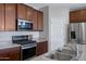 Contemporary kitchen showcasing stainless steel appliances, dark wood cabinets, and granite countertops at 25974 W Horsham Dr, Buckeye, AZ 85396