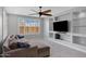 Comfortable living room featuring a ceiling fan, a sectional sofa, and custom shelving with built in media center at 25974 W Horsham Dr, Buckeye, AZ 85396