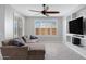 The living room showcases modern tile flooring, an oversized sectional sofa, a ceiling fan and backyard views at 25974 W Horsham Dr, Buckeye, AZ 85396