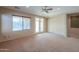Neutral living room showcasing plush carpeting, multiple windows, and French doors leading to outdoor space at 36255 W Marin Ave, Maricopa, AZ 85138