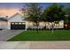 Charming home exterior with a black garage door, lush lawn, and manicured landscaping at 3808 E Fairmount Ave, Phoenix, AZ 85018