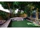Backyard with artifical grass, a stone wall, and mature trees for privacy and shade at 3931 E Crest Ln, Phoenix, AZ 85050