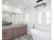 Bright bathroom featuring dual vanity, modern tub, decorative chandelier, and plantation shutters for natural light at 3931 E Crest Ln, Phoenix, AZ 85050