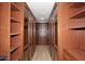 Spacious walk-in closet with wood shelving, glass-front cabinets, and ample storage space at 3931 E Crest Ln, Phoenix, AZ 85050