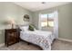 Cozy bedroom features a decorative floral comforter, a wooden cabinet, and a bright sunny window at 40807 N Barnum Way, Anthem, AZ 85086