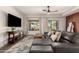 Comfortable living room with a large leather sectional couch, a ceiling fan, and backyard patio access at 40807 N Barnum Way, Anthem, AZ 85086
