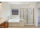 Bright bathroom with a bathtub, glass-enclosed shower, and large window at 41344 W Laramie Rd, Maricopa, AZ 85138
