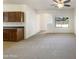 Open-concept living space with hardwood cabinets, neutral carpet, and bright natural light at 41344 W Laramie Rd, Maricopa, AZ 85138