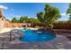 Beautiful backyard showcasing a swimming pool with rock features, a covered patio, and mature trees at 4321 E Morenci Rd, San Tan Valley, AZ 85143